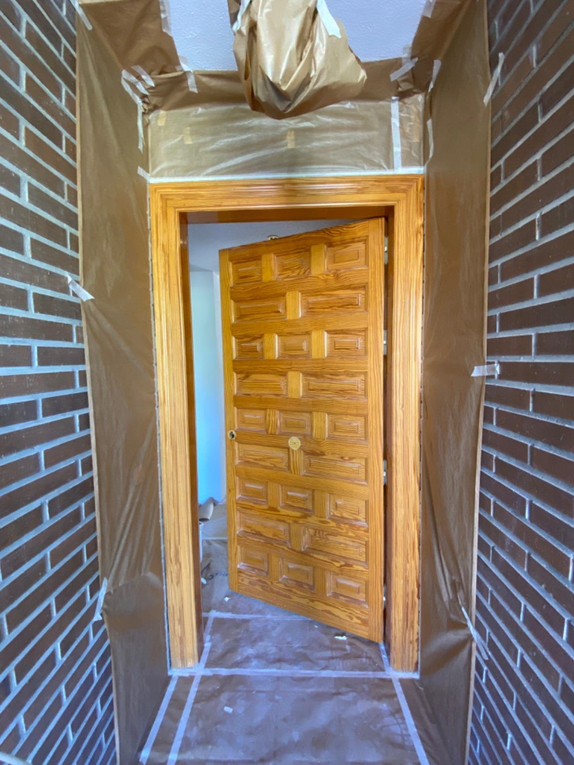 Puerta exterior de madera antes de la reforma en vivienda con ladrillo visto